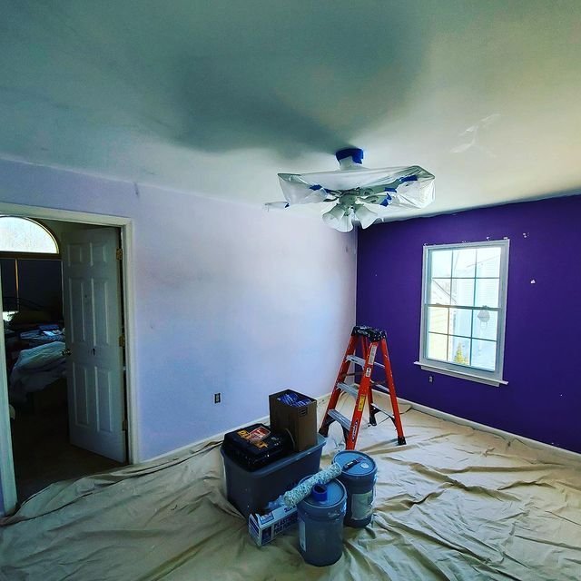 Bedroom mid-job with taped fixtures and drop cloths